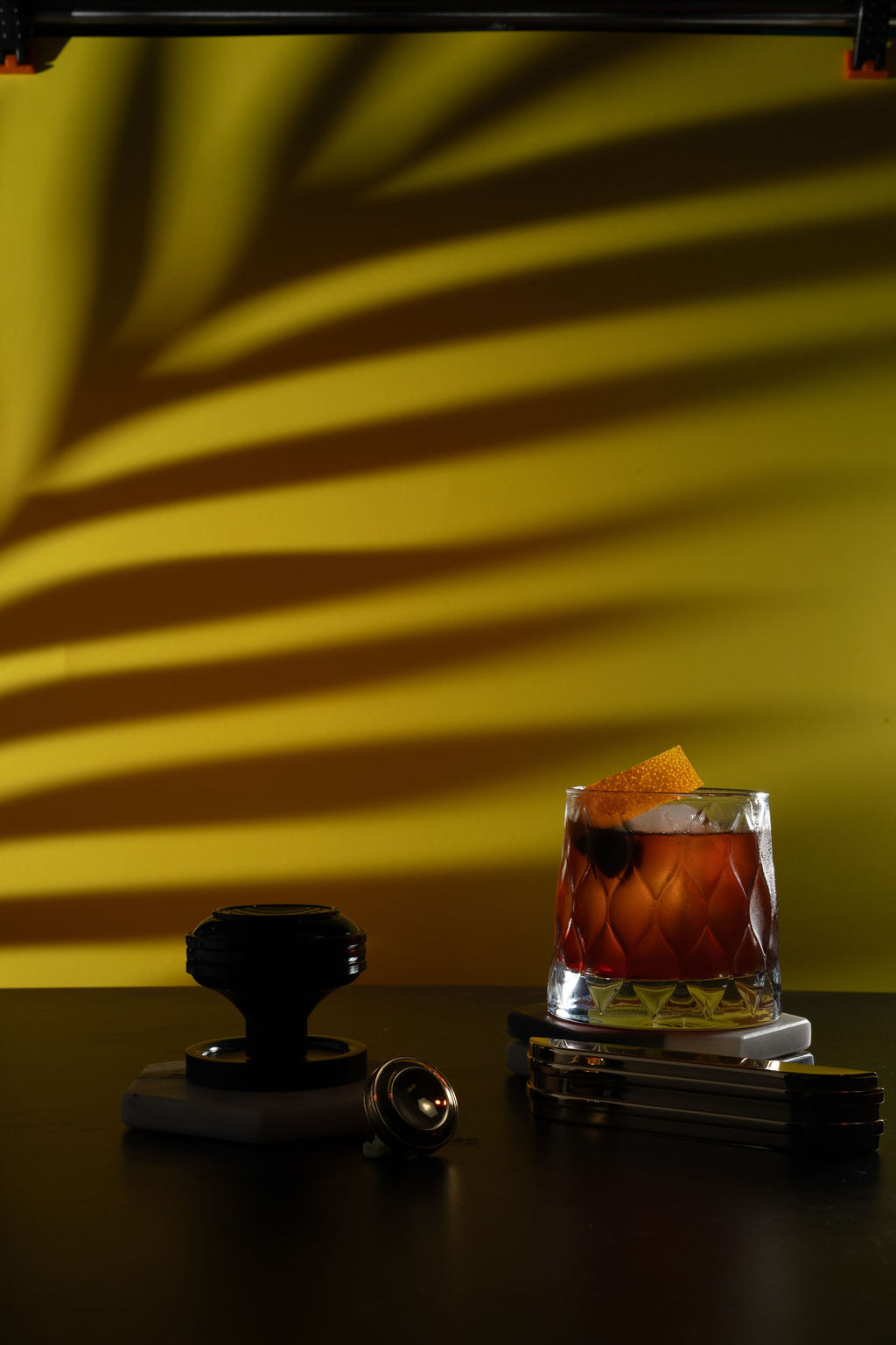 Amber old fashioned with palm leaf shadows on a golden backdrop