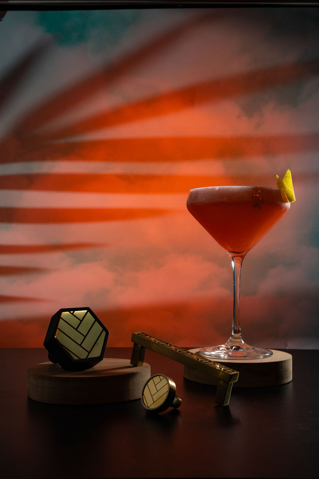 Orange coupe cocktail with art deco accessories and warm sunset backdrop