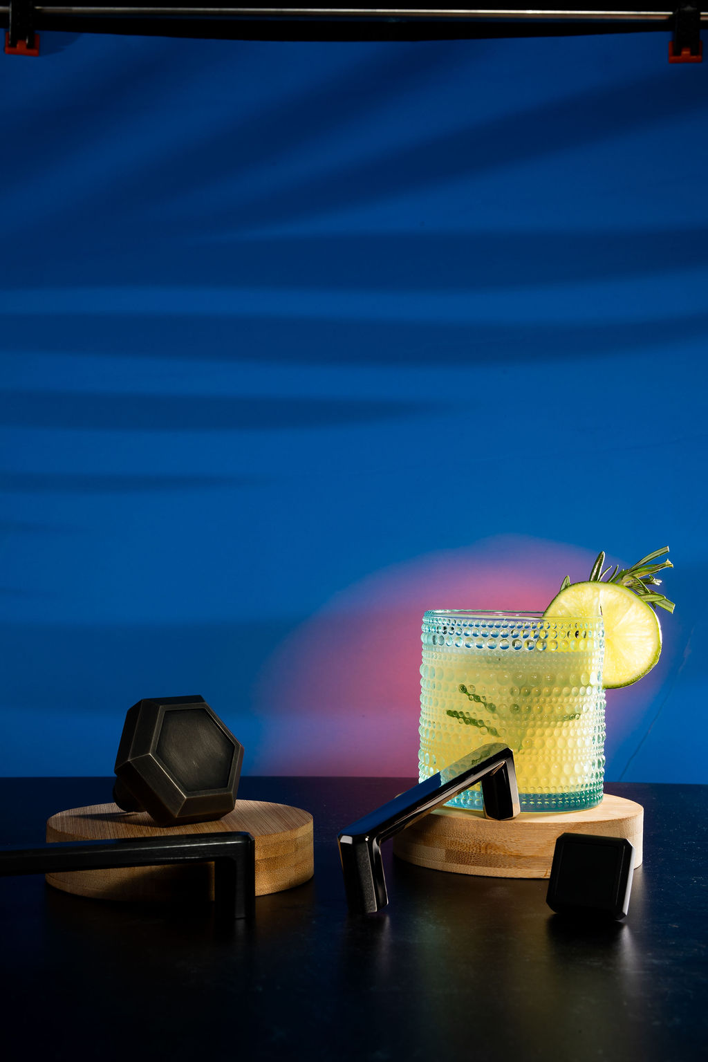 Lime cocktail in a hobnail glass with blue and purple backdrop